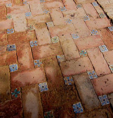 close up of historic red brick with decorative Spanish tiles embedded in this historic public plaza in Seville, Spain.