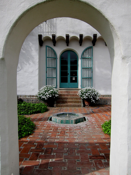 a historic Spanish style fountain in a brick courtyard at Casa del Herrero in Montecito, California - photo framed by a thick plaster archway