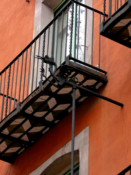 Spanish Revival style iron balcony with decorative tile installed underneath iron deck. Photo taken in the Barri Gotic district in old part of Barcelona, Spain