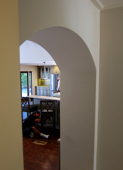 A talented general contractor puts the final touches  on details of a modern kitchen renovation in Montecito, California.  A thick decorative archway frames the shot