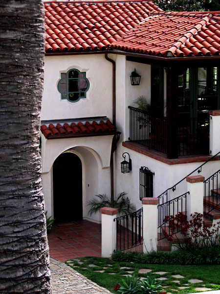 A custom two story Santa Barbara Spanish style home with tile roof entry stoop and quatrafoil window.